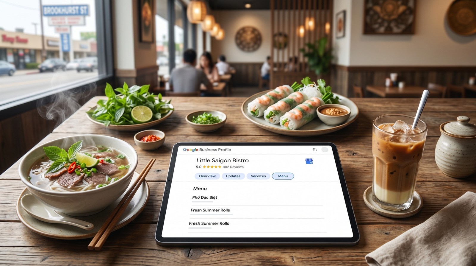 A wide 16:9 SEO banner showing a tablet with Google Business profile menu and 5-star reviews surrounded by Vietnamese dishes on a Brookhurst St restaurant table